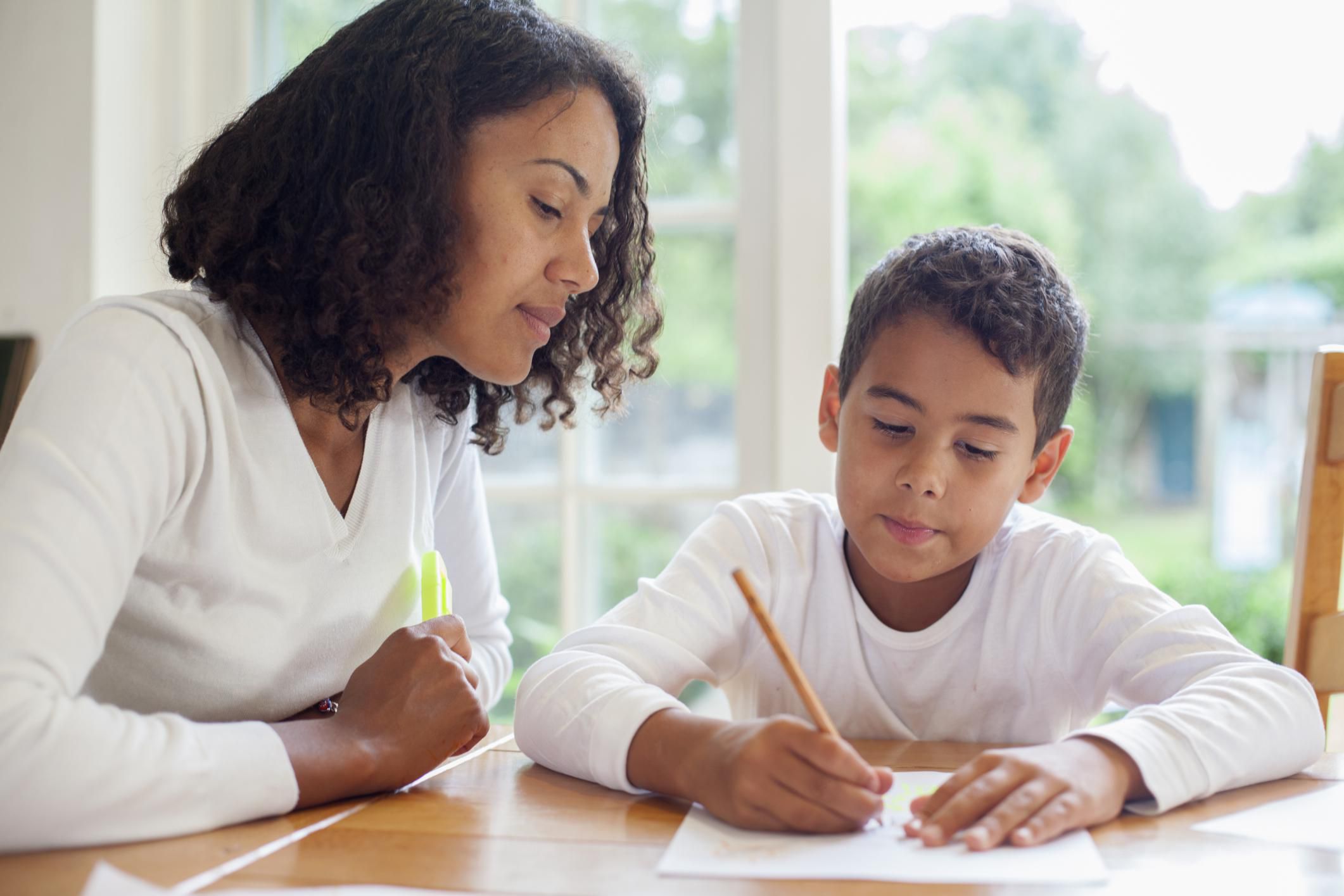 Mom helps son with homework at the kitchen table